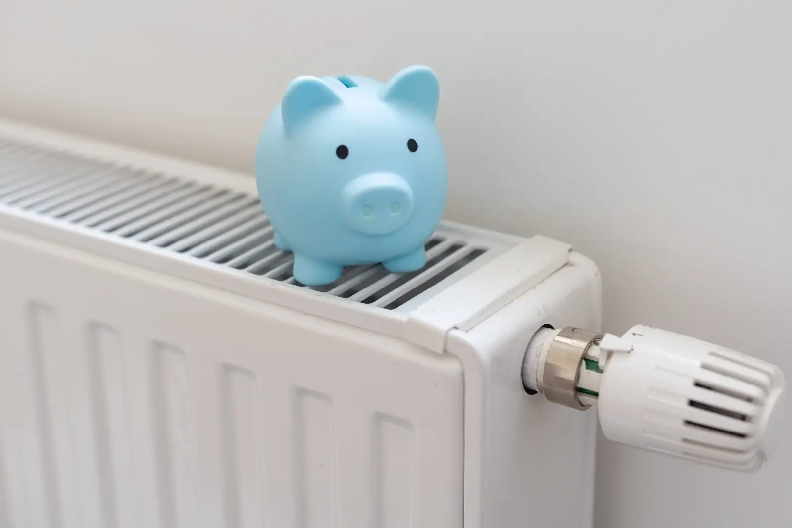 Świnka skarbonka na kaloryferze symbolizująca oszczędności przy dofinansowaniu wymiany pieca w Jaworznie